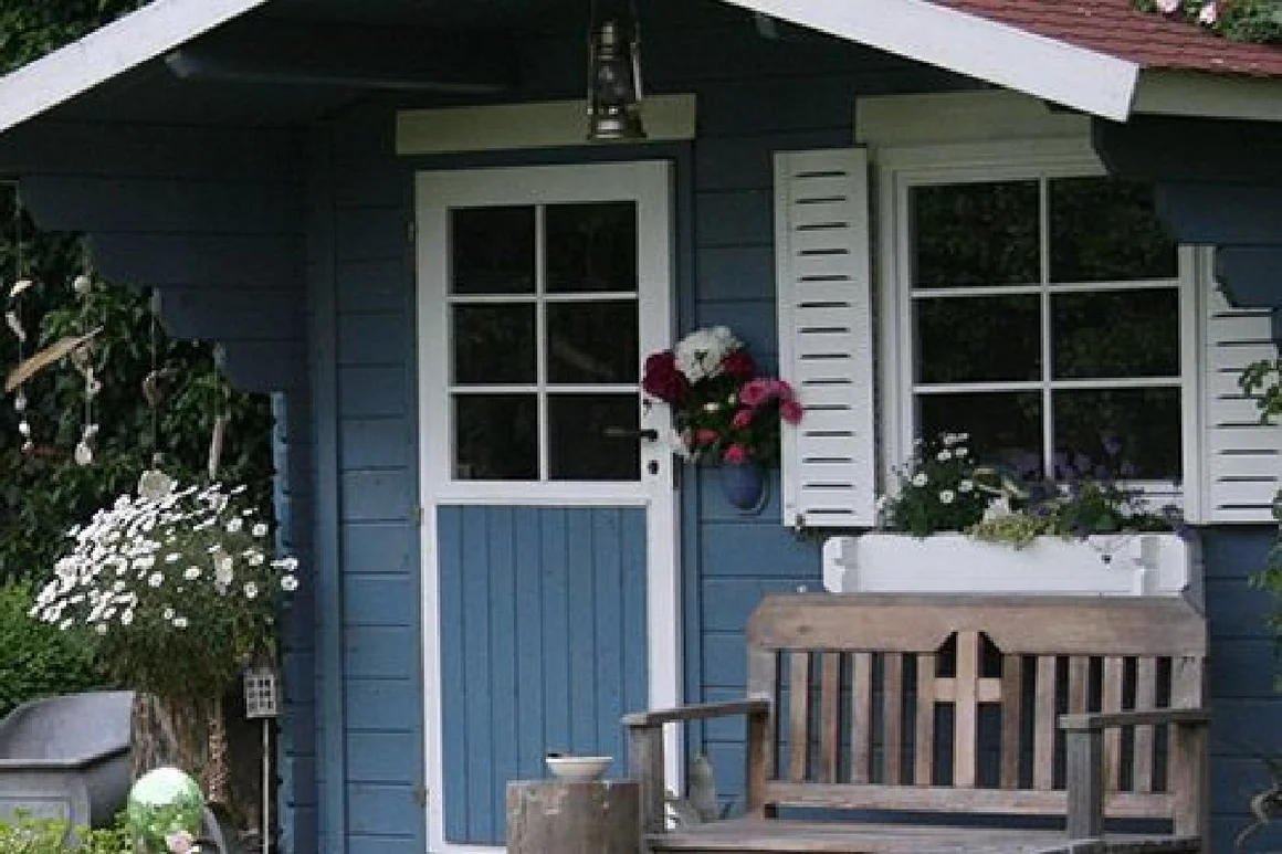 Blaues Gartenhaus mit weißer Tür und Fensterläden